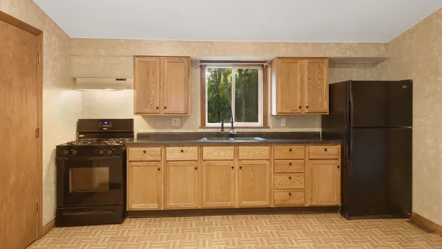 a kitchen with granite countertop a refrigerator stove and sink