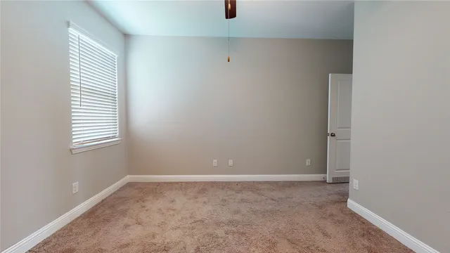 an empty room with closet and a ceiling fan