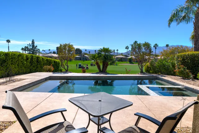 a view of a swimming pool with chairs in patio