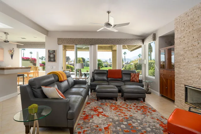 a living room with furniture ceiling fan and a large window