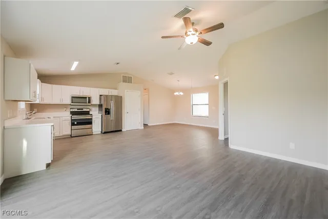 a view of an empty room with a kitchen and a stove top oven