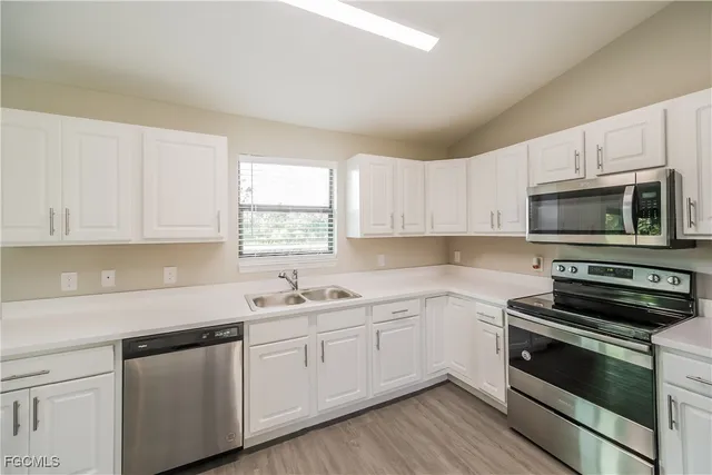 a kitchen with white cabinets stainless steel appliances and sink