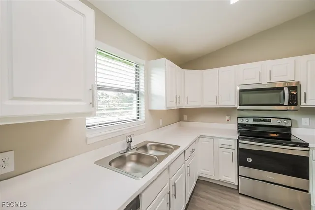 a kitchen with granite countertop a sink a counter space appliances and cabinets