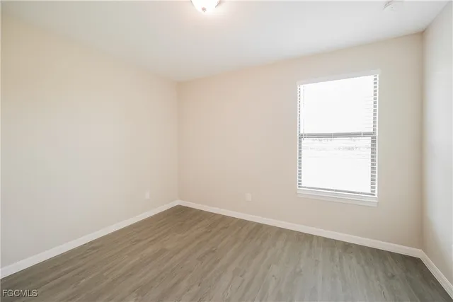 an empty room with wooden floor and window