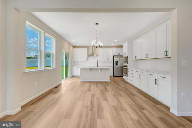 a kitchen with stainless steel appliances granite countertop a stove a sink and white cabinets with wooden floor