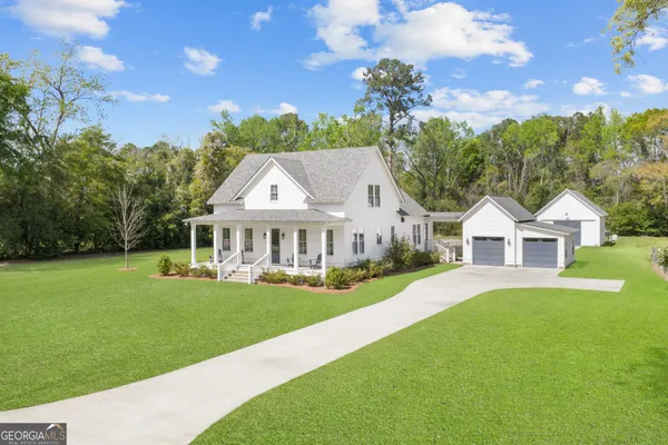 a front view of a house with a garden and trees