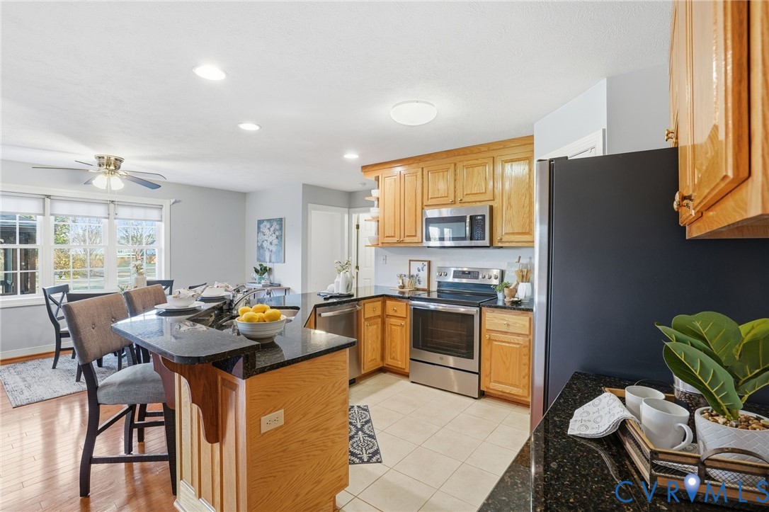 8420 Lee Davis Road Mechanicsville, VA 23116 - Photo 10 of 45 a kitchen with stainless steel appliances granite countertop a stove a refrigerator a dining table and chairs with wooden floor