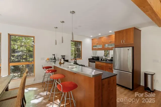 a kitchen with stainless steel appliances granite countertop a refrigerator a sink dishwasher a stove and white countertops with wooden floor