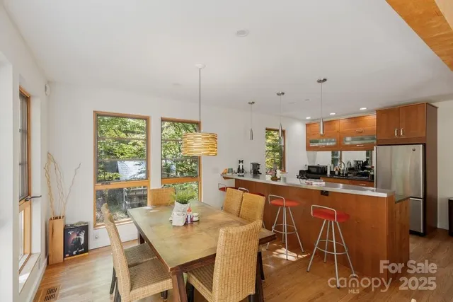 a kitchen with stainless steel appliances granite countertop a table chairs and a wooden floor