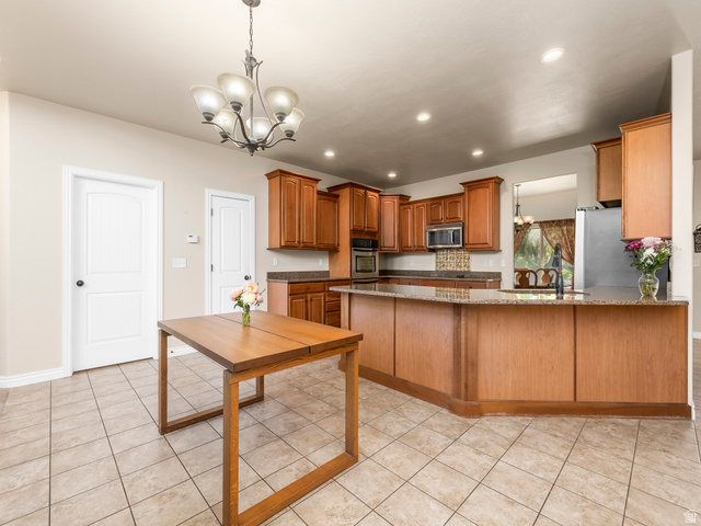 255 East 1200 North Mapleton, UT 84664 - Photo 6 of 37 Kitchen featuring extensive wood cabinetry, stone countertops, integrated stainless steel appliances, and a tiled backsplash
