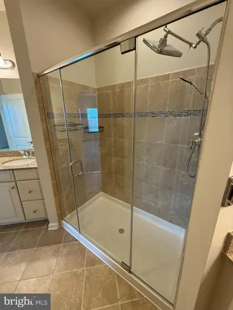 a bathroom with a granite countertop sink a mirror and a shower