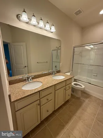 a bathroom with a granite countertop sink a large mirror and a toilet