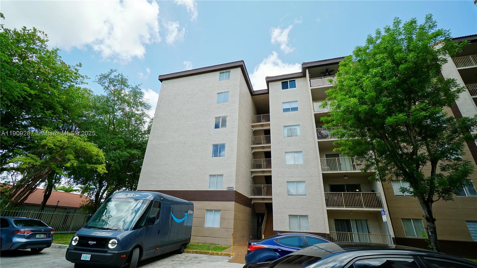 15231 Southwest 80th Street, Unit 101 Miami, FL 33193 - Photo 19 of 19 a front view of a building with parking space and trees