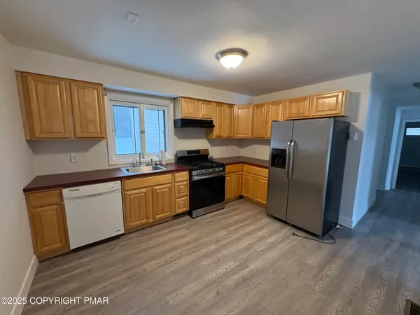 a kitchen with granite countertop a refrigerator cabinets and wooden floor