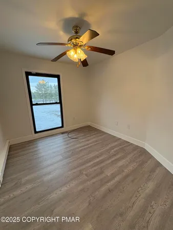 an empty room with wooden floor closet and fan