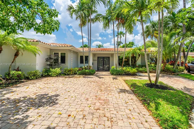 a front view of a house with garden and trees