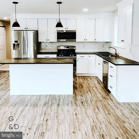 a kitchen with stainless steel appliances granite countertop a refrigerator a stove top oven a sink and cabinets