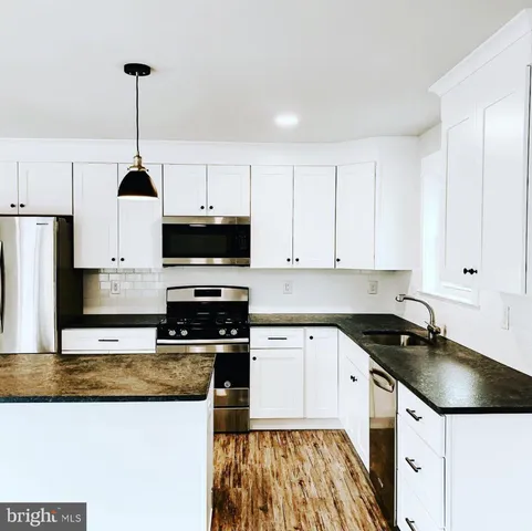 a kitchen with granite countertop a sink a counter top space appliances and cabinets