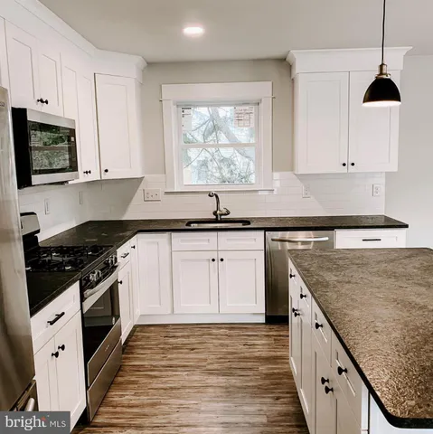 a kitchen with granite countertop a sink a stove and cabinets