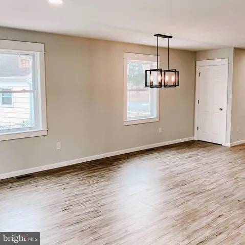 an empty room with wooden floor cabinet and windows