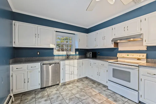 a kitchen with granite countertop white cabinets and white appliances