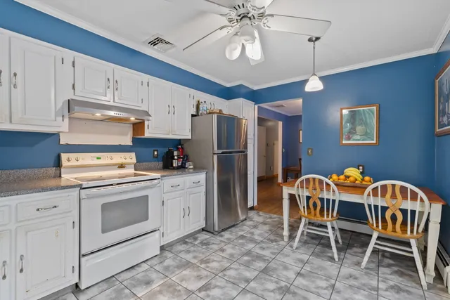 a kitchen with stainless steel appliances granite countertop a dining table chairs and white cabinets