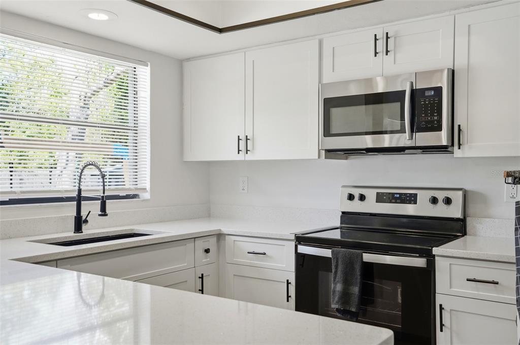 5485 Pinehurst Drive Spring Hill, FL 34606 - Photo 13 of 45 a kitchen with stainless steel appliances a stove a microwave and cabinets