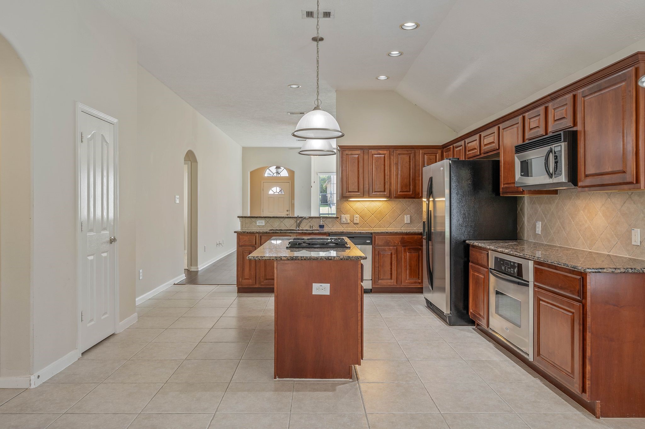 166 April Cove Montgomery, TX 77356 - Photo 11 of 37 Central island with cooktop serves as a functional workspace and gathering spot.