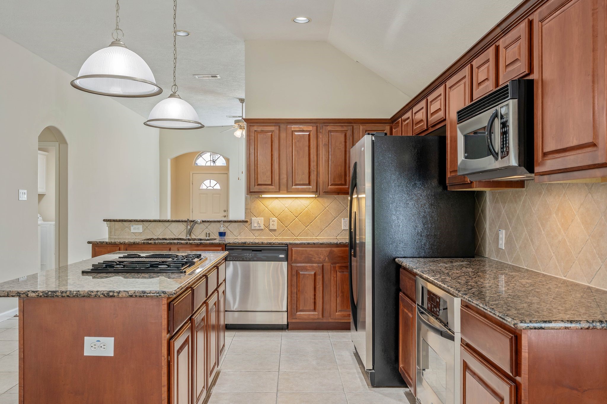 166 April Cove Montgomery, TX 77356 - Photo 10 of 37 Well-appointed kitchen with gas cooktop island, breakfast bar seating, under-cabinet lighting, and ample cabinetry.