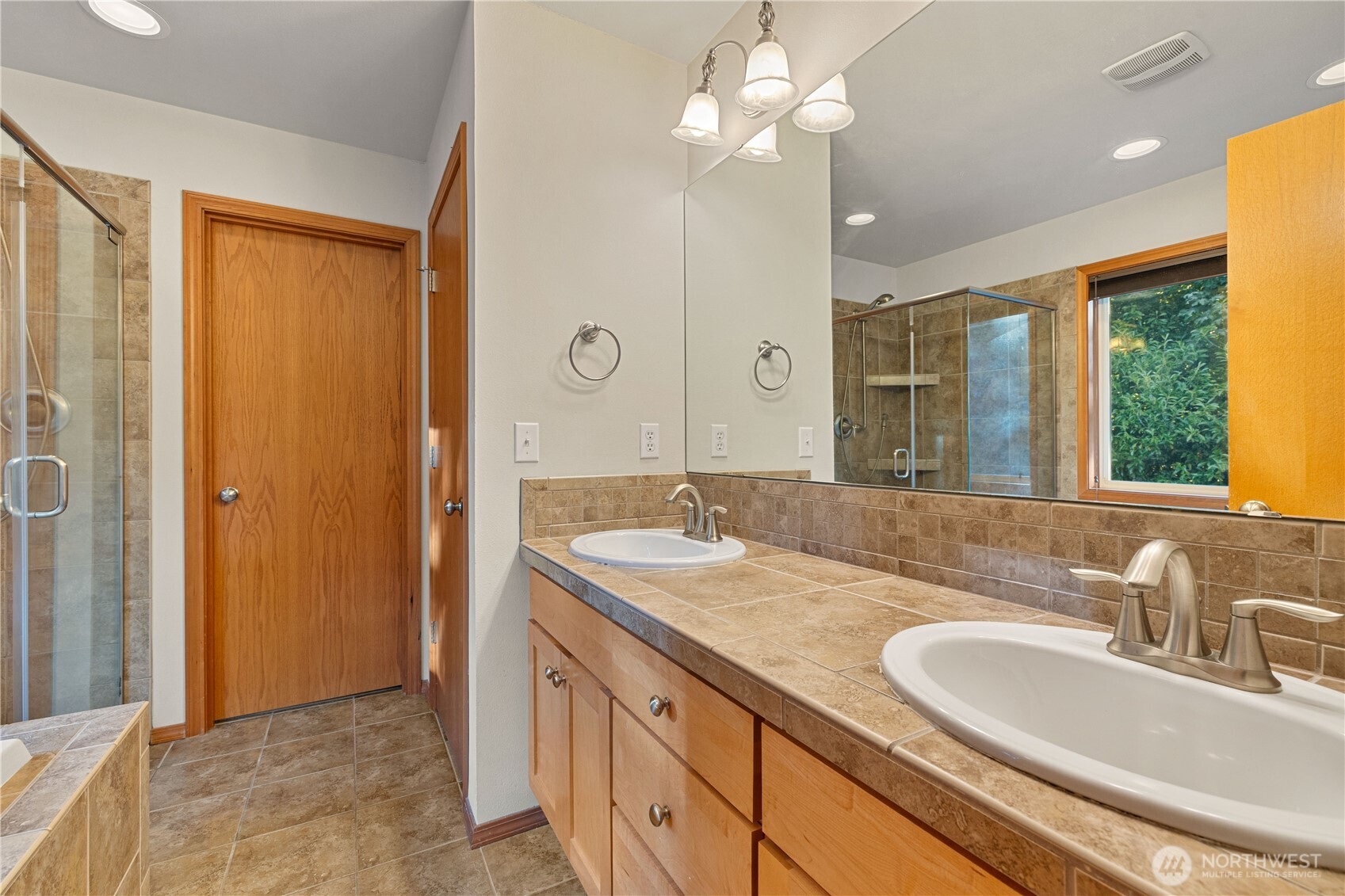 9301 53rd Avenue South Seattle, WA 98118 - Photo 9 of 25 a bathroom with a granite countertop double vanity sink a mirror and a shower