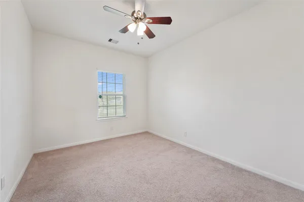 an empty room with a window and a fan
