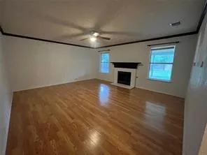 an empty room with windows fireplace and wooden floor