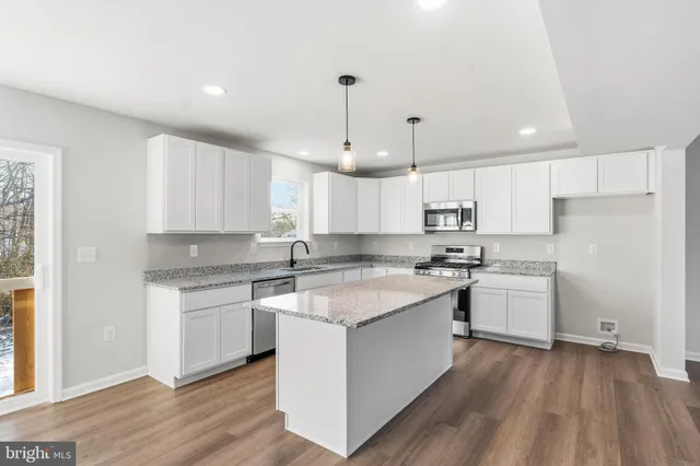 a kitchen with a sink stove a refrigerator and white cabinets