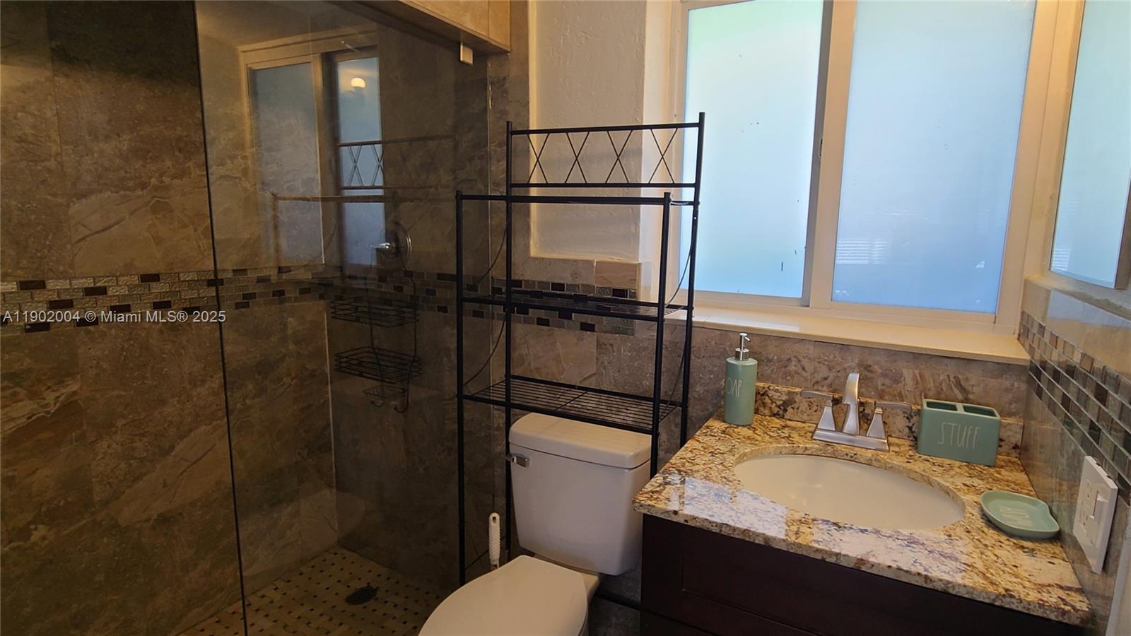 3221 Northeast 7th Street, Unit 2 Pompano Beach, FL 33062 - Photo 7 of 10 a bathroom with a granite countertop sink toilet and shower