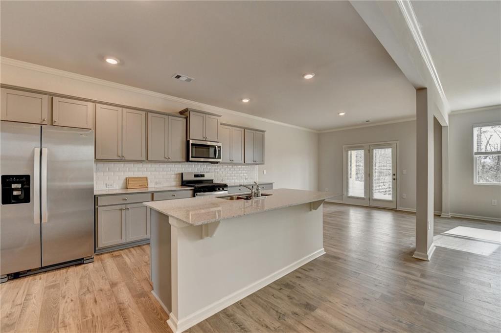 4067 Peregrine Way Gainesville, GA 30506 - Photo 6 of 52 a kitchen with stainless steel appliances granite countertop a refrigerator a sink dishwasher a stove and white countertops with wooden floor