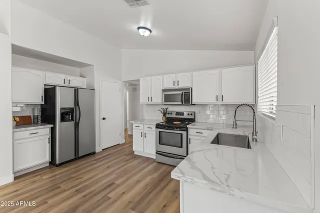 a kitchen with stainless steel appliances granite countertop a refrigerator stove microwave and sink