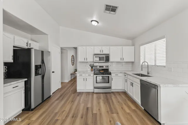 a kitchen with stainless steel appliances granite countertop a stove top oven a refrigerator a sink dishwasher with a dining table and chairs