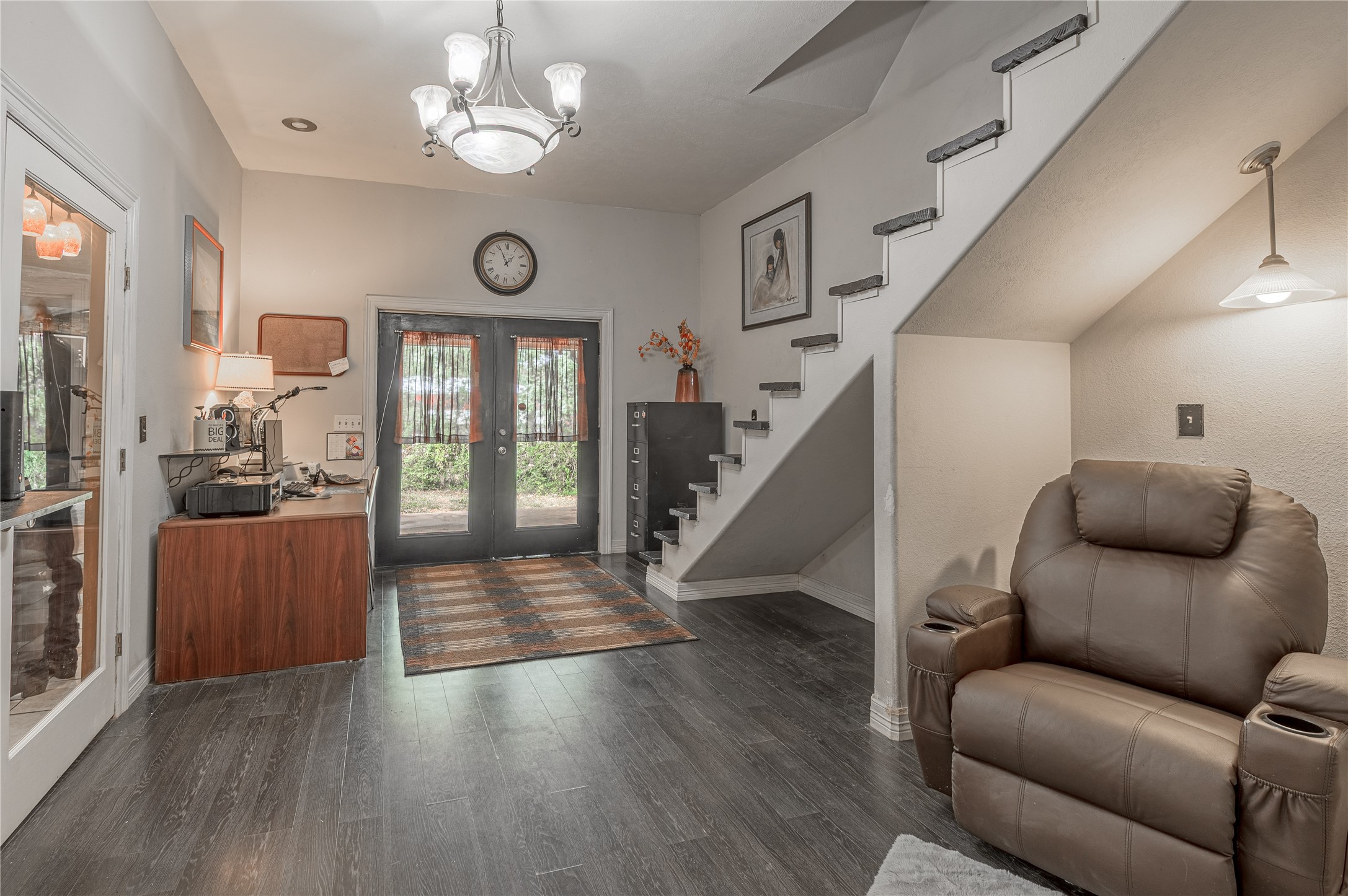 47-57 Stage Coach Road Coldspring, TX 77331 - Photo 9 of 50 Inviting area featuring sleek dark wood flooring, a seating area, and elegant staircase, all illuminated by modern lighting.