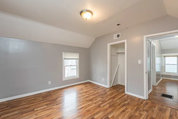 an empty room with wooden floor and windows