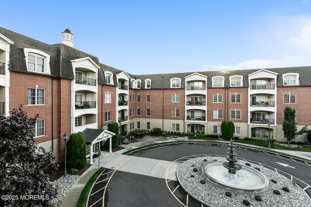 a front view of a building with street view and a fountain