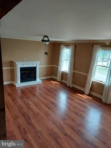 an empty room with wooden floor fireplace and windows