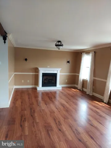 an empty room with wooden floor fireplace and windows