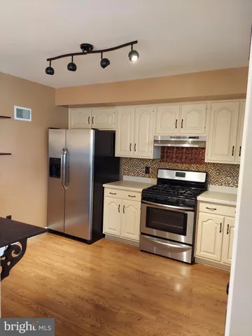 a kitchen with granite countertop a refrigerator and a stove top oven