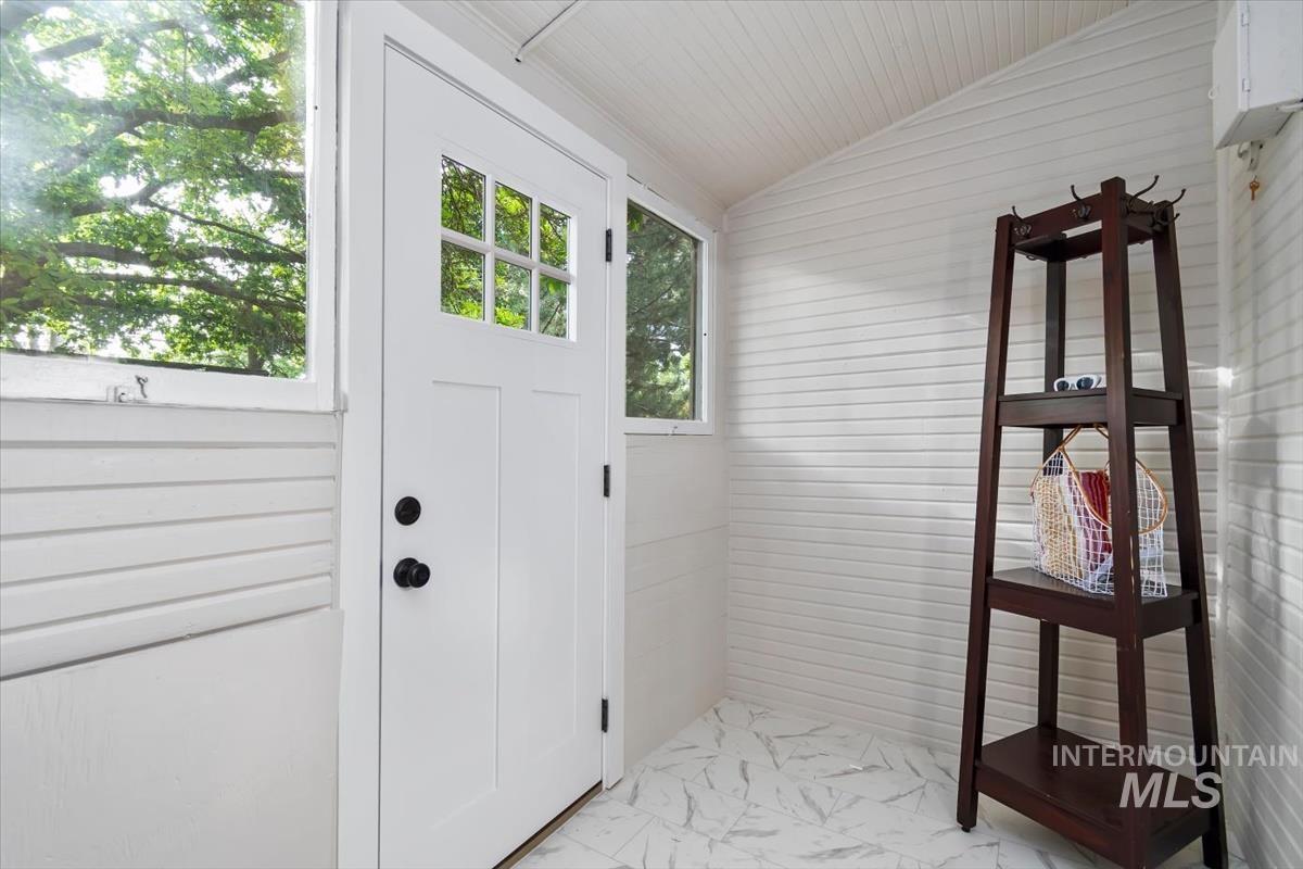 910 North 16th Street Boise, ID 83702 - Photo 26 of 47 Bright entry area featuring a white multi-pane door with matte black hardware, white horizontal wall paneling, white tongue-and-groove ceiling, and light-toned patterned floor tiles