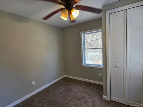 an empty room with a window and a chandelier fan