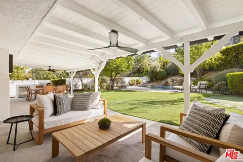 a view of a patio with table and chairs potted plants and floor to ceiling window