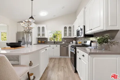a kitchen with stainless steel appliances granite countertop a sink dishwasher a stove a dining table and chairs with wooden floor