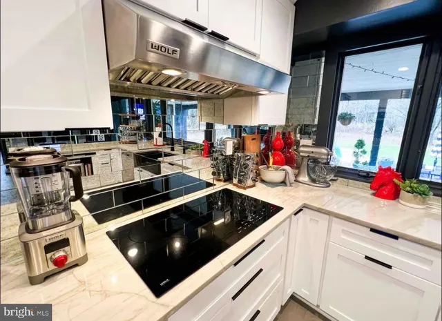 a kitchen with stainless steel appliances kitchen island granite countertop a stove and white cabinets