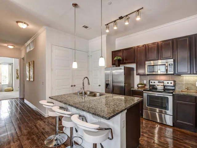a kitchen with stainless steel appliances granite countertop a sink a stove and a refrigerator