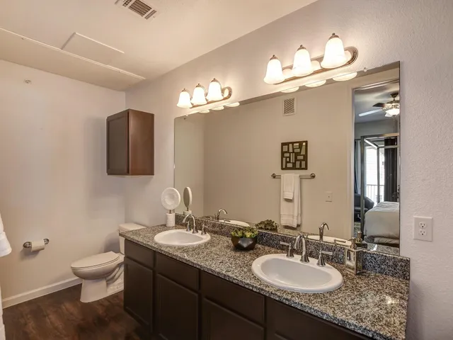 a bathroom with a granite countertop sink a toilet and mirror